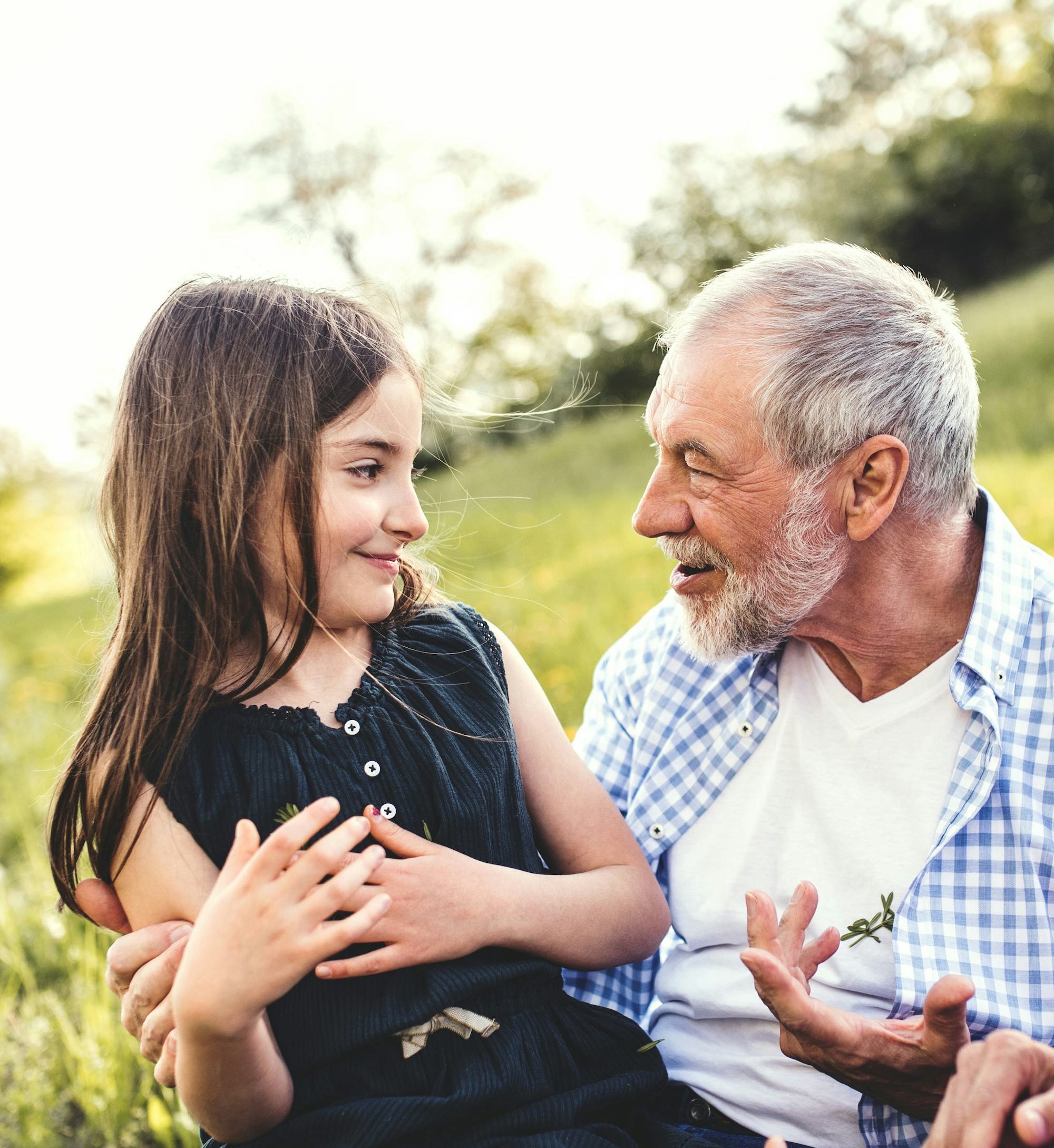 Grandpa lovingly explaining something to his granddaughter sitting in his lap