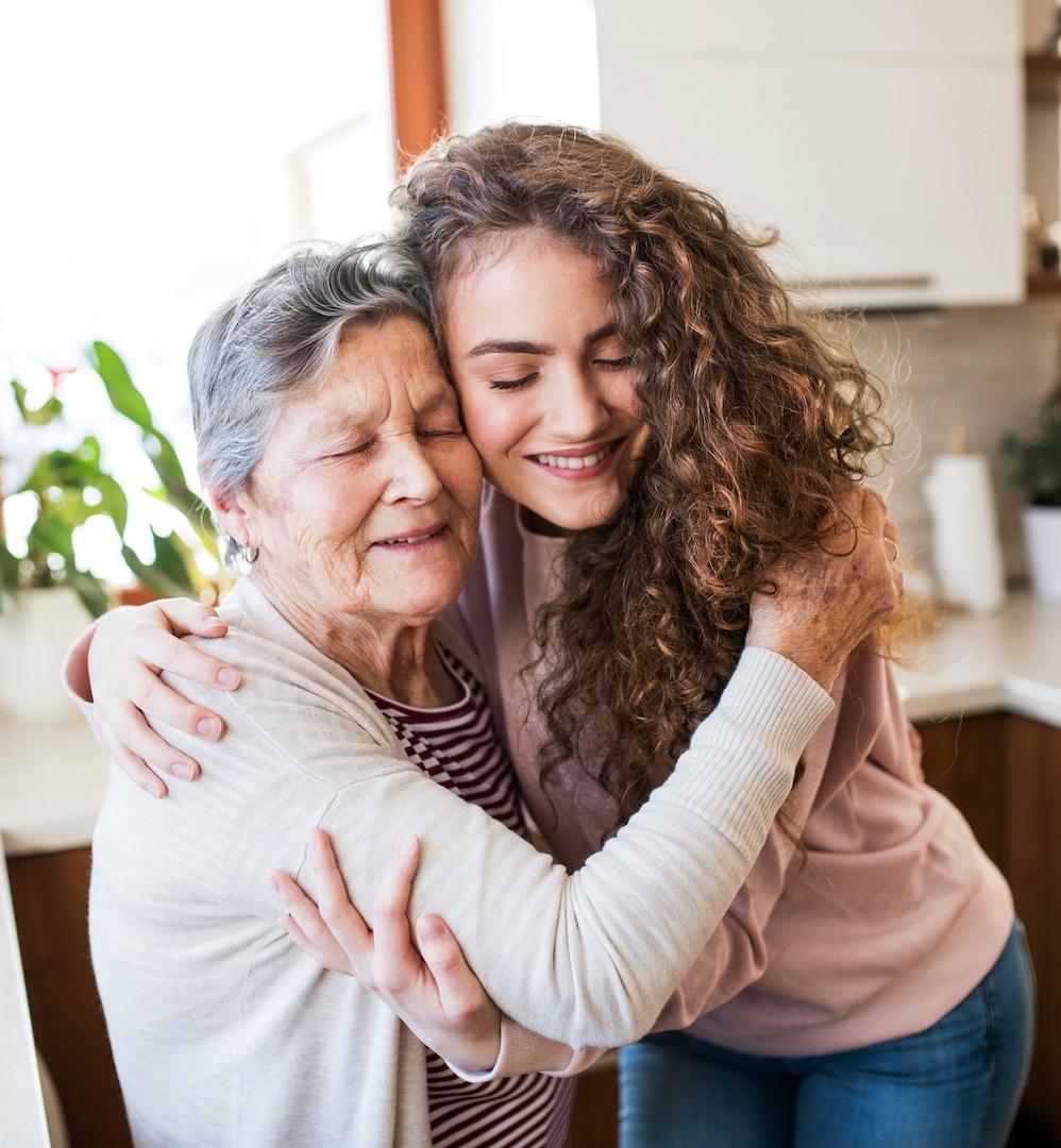 Young woman lovingly hugs her grandmother