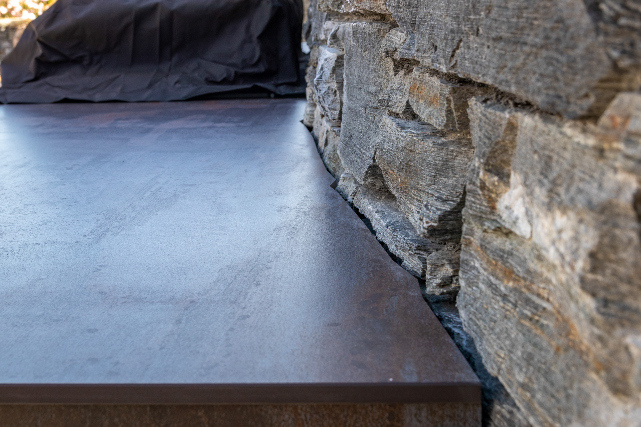 Close-up of a textured concrete surface alongside a rough stone wall.