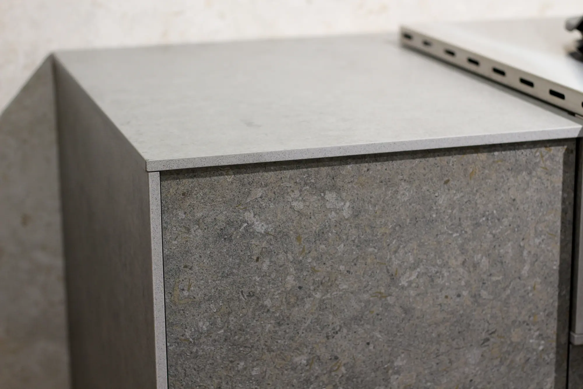 Close-up of a corner of a stone-textured grey cabinet or countertop with a smooth top surface.