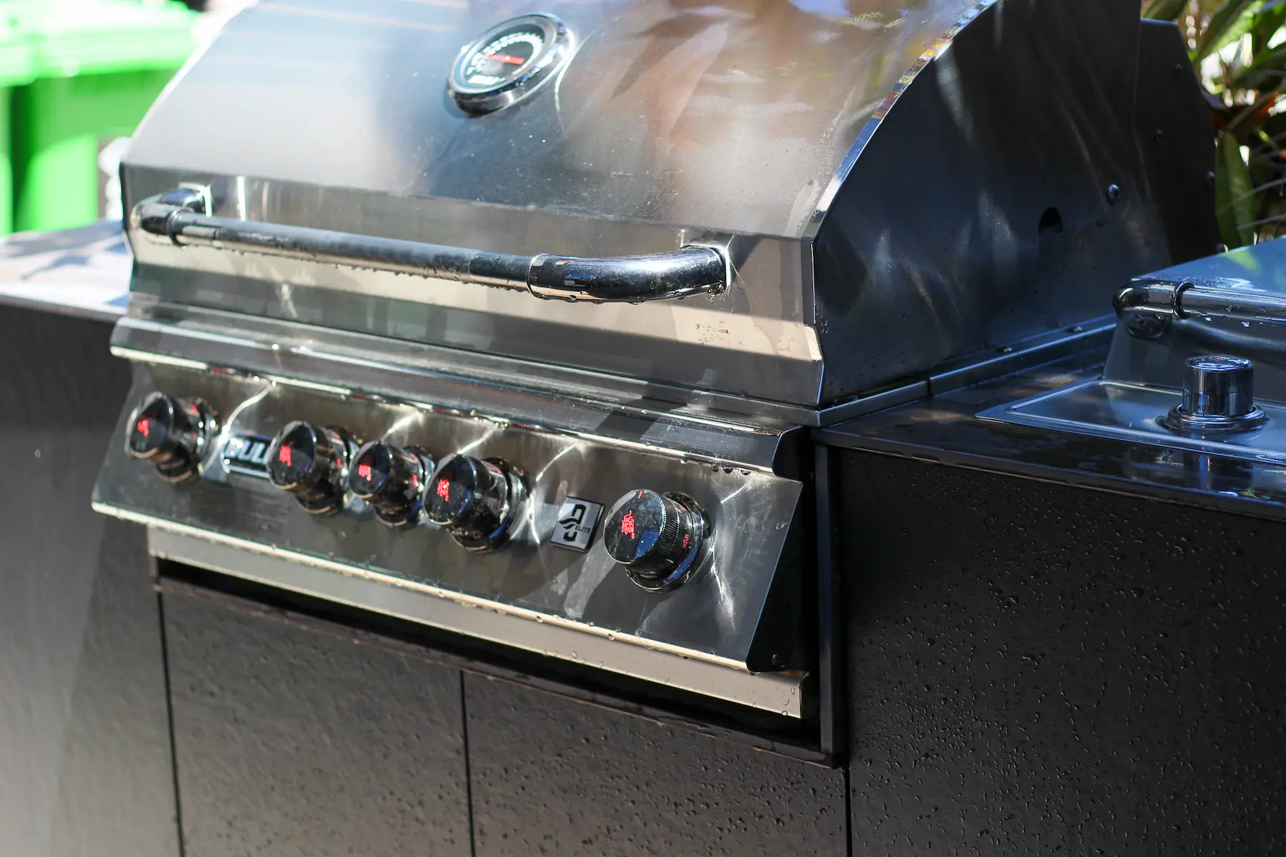 Close-up of a modern stainless steel outdoor gas barbecue grill with control knobs and a temperature gauge.