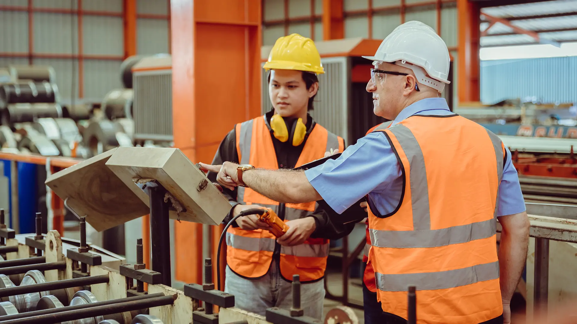 Senior operations supervisor training inexperienced frontline worker on conveyor belt operations in manufacturing warehouse