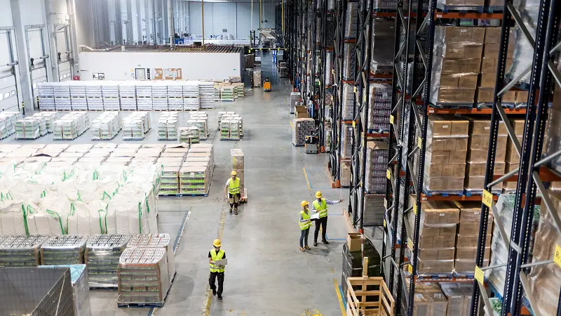 Blurred motion of busy warehouse manager in uniform reading online records on tablet while hurrying to shipment station