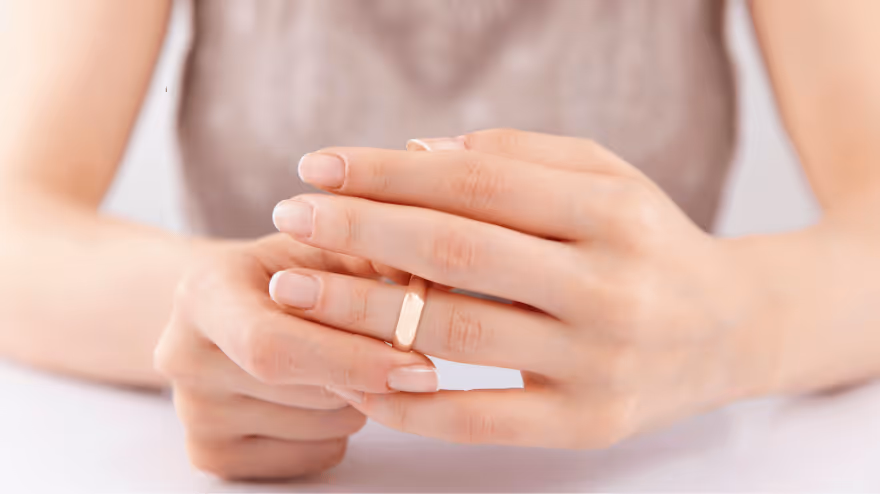 Close-up of a person’s hands removing a wedding ring.