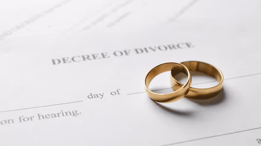 Two gold wedding rings rest on a divorce decree document.