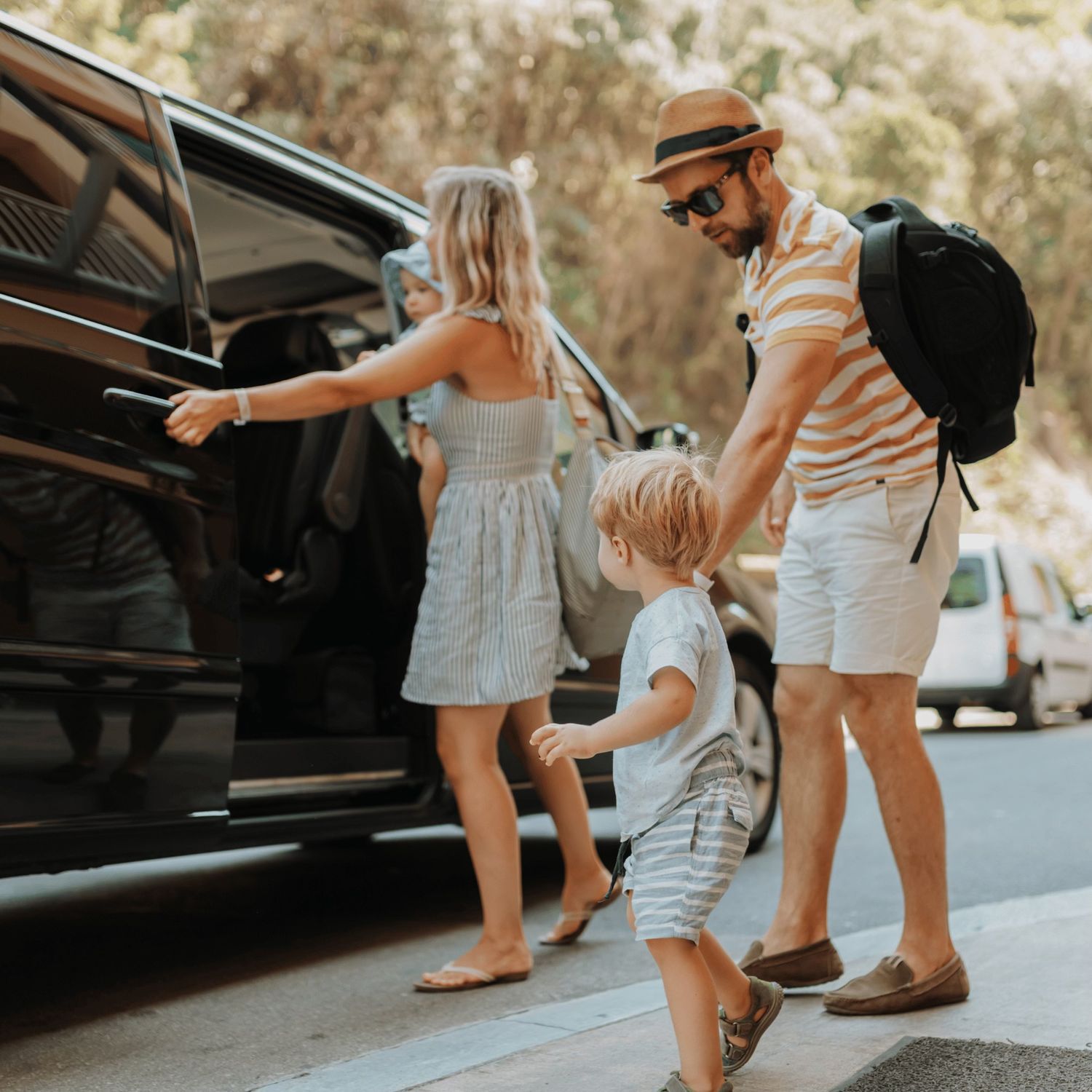 Family with two children standing beside a car