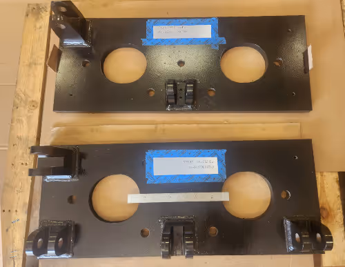 Fabricated and CNC machined steel base plates with circular cutouts and welded mounts by Burns Machine Company.