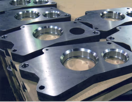 CNC machined metal mounting plates with precision bores, manufactured by Burns Machine Company.