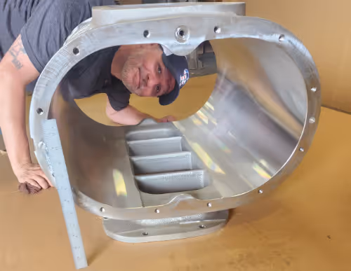 Large CNC machined Roots blower housing with technician showing scale, made by Burns Machine Company.