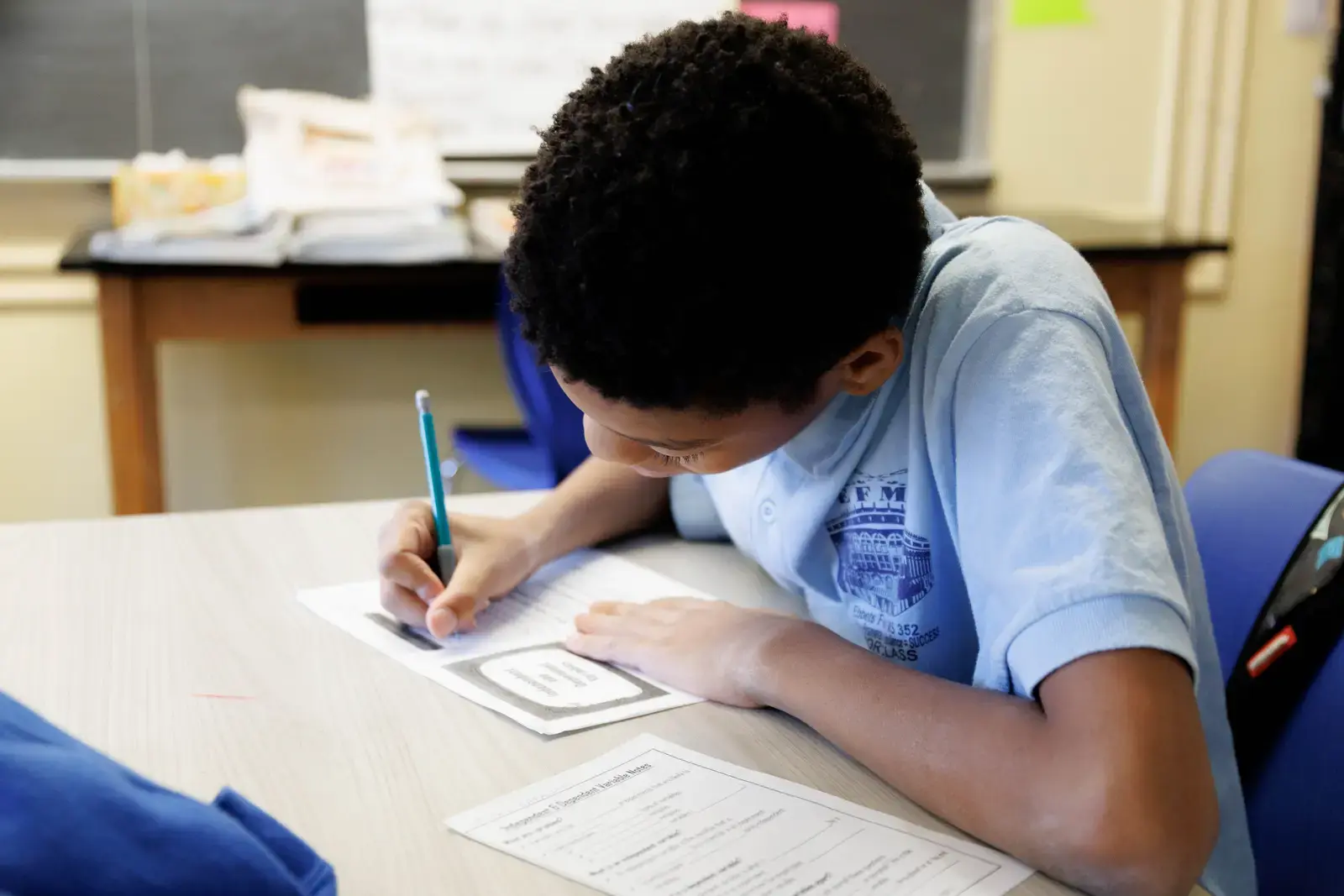 Student writing on a worksheet at a classroom desk