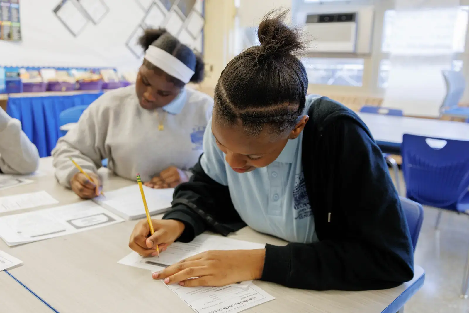Two middle school students writing with pencils during a classroom assignment