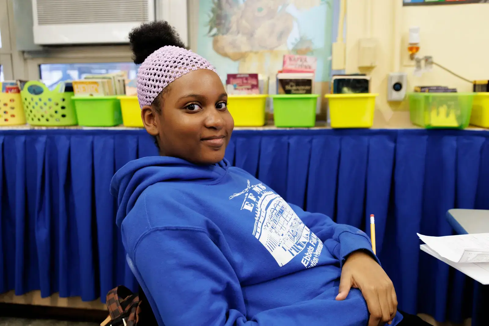 Student sitting at desk in classroom holding a pencil