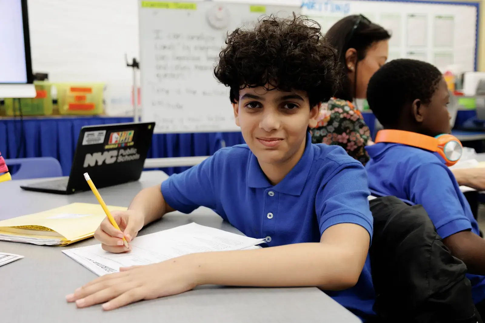 Middle school student writing at desk in NYC Public Schools classroom