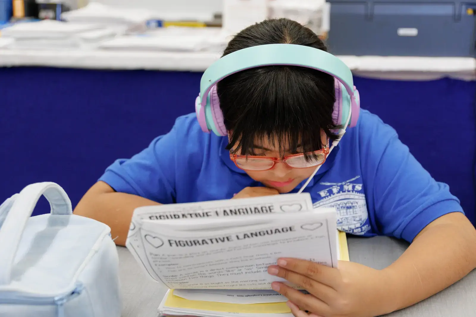 Student wearing headphones reads a figurative language worksheet at desk