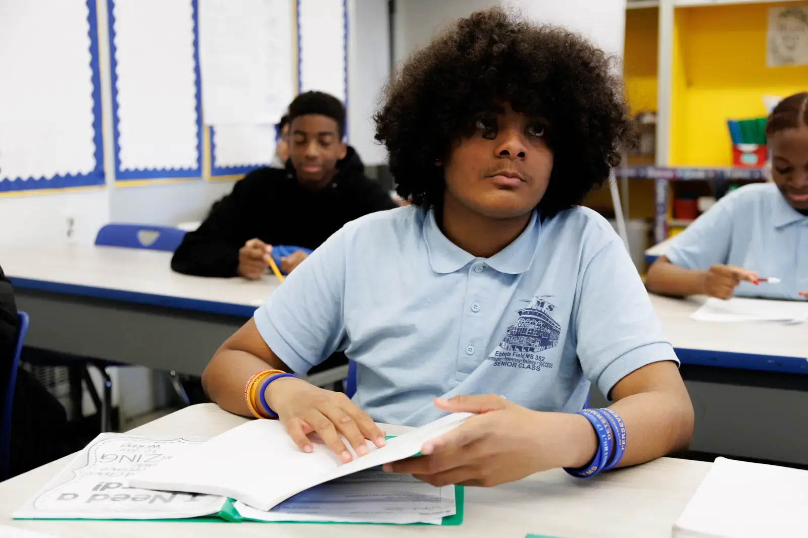 Middle school student in uniform reading at classroom desk