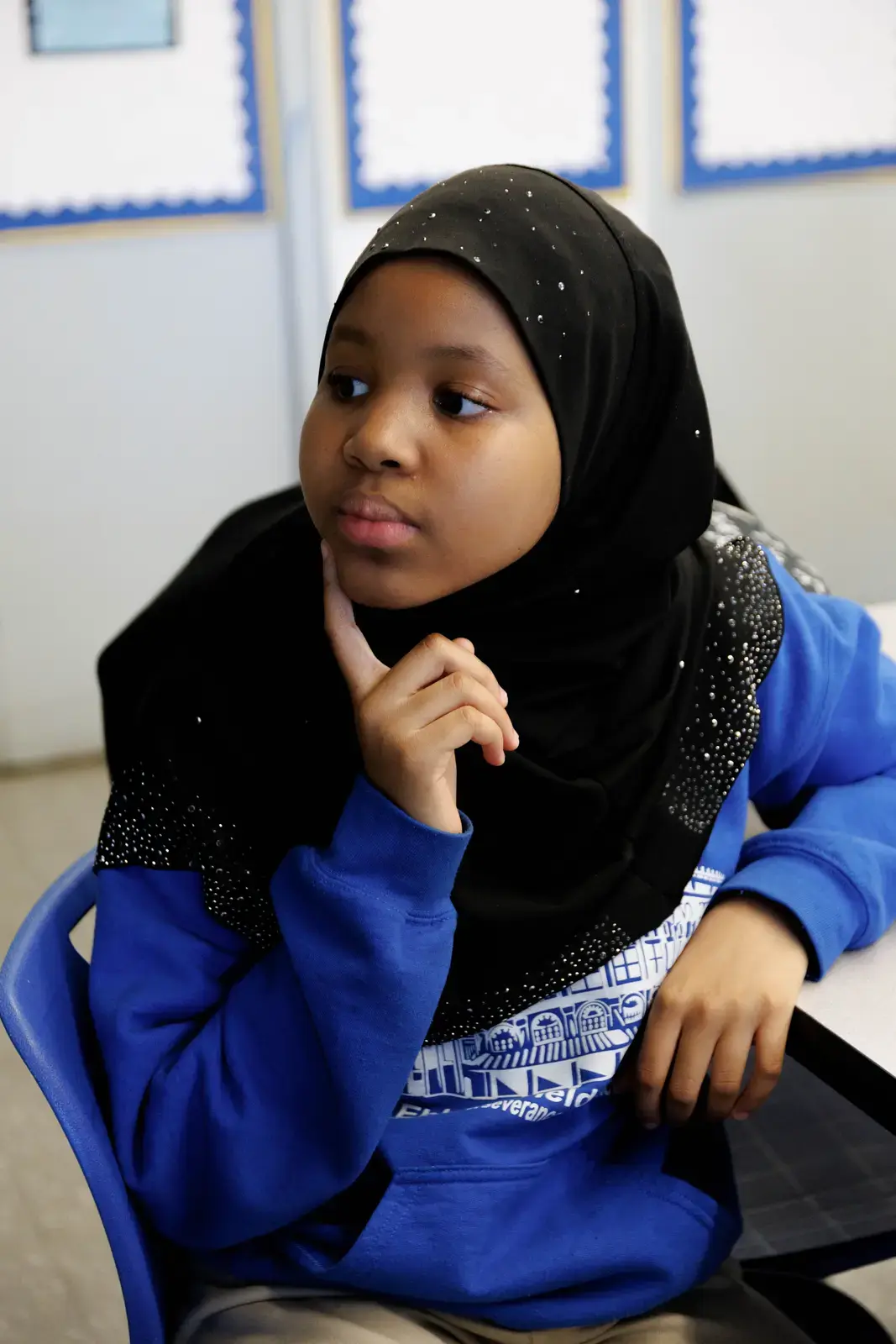 Student sitting at desk with thoughtful expression in classroom