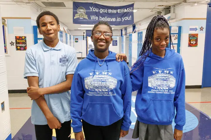 Three EFMS students smiling together in school hallway