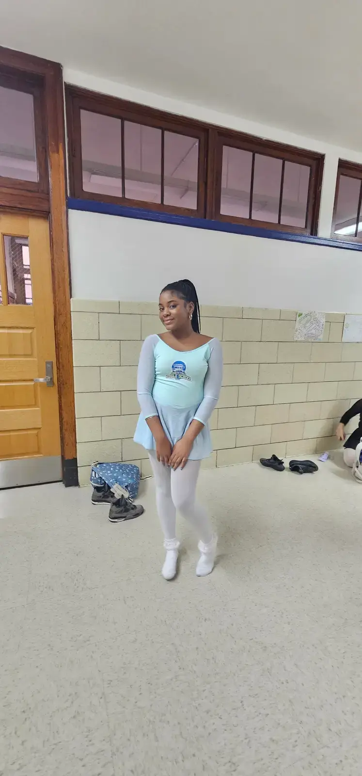 Student in ballet leotard and tights posing in school hallway