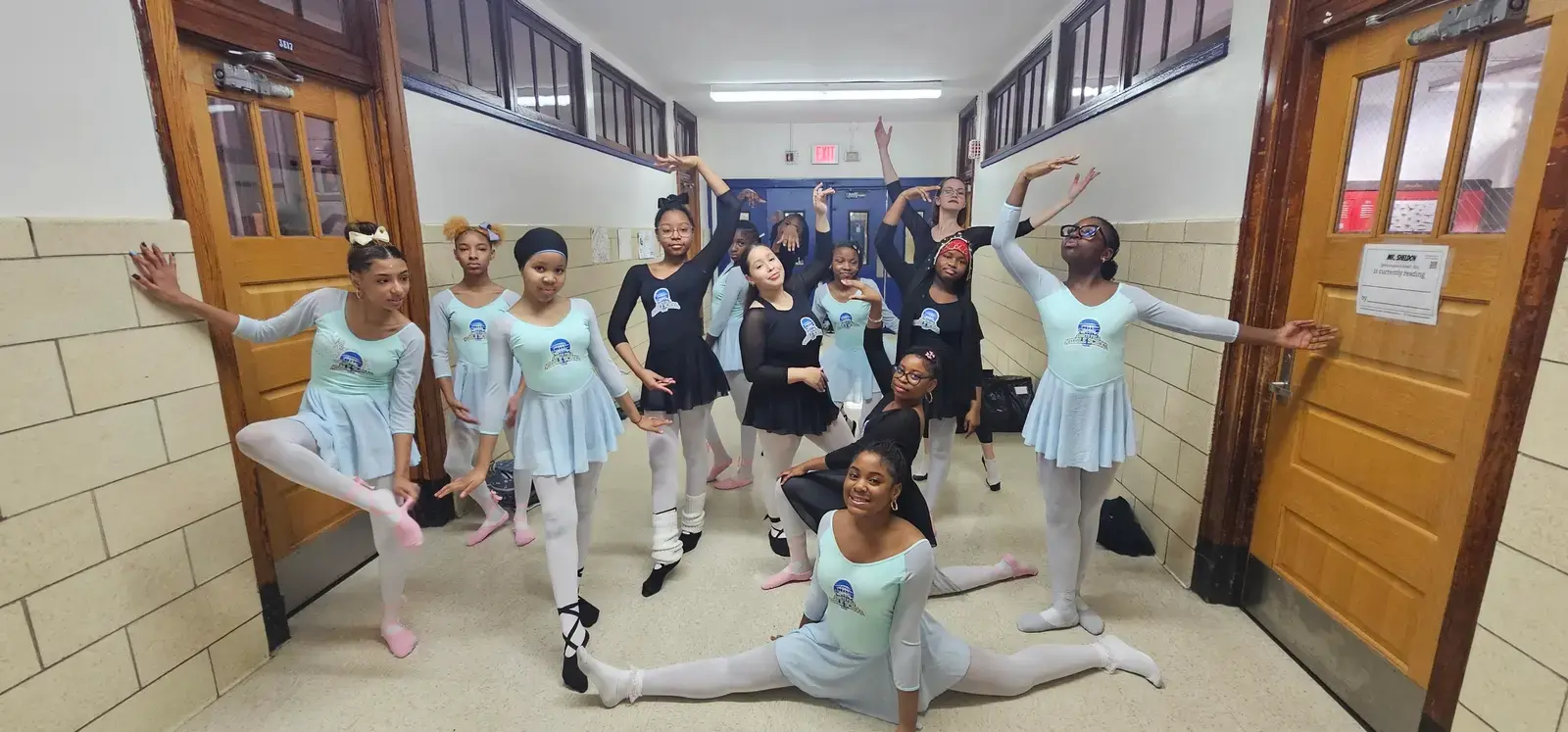 Student ballet dancers posing in school hallway in dance costumes