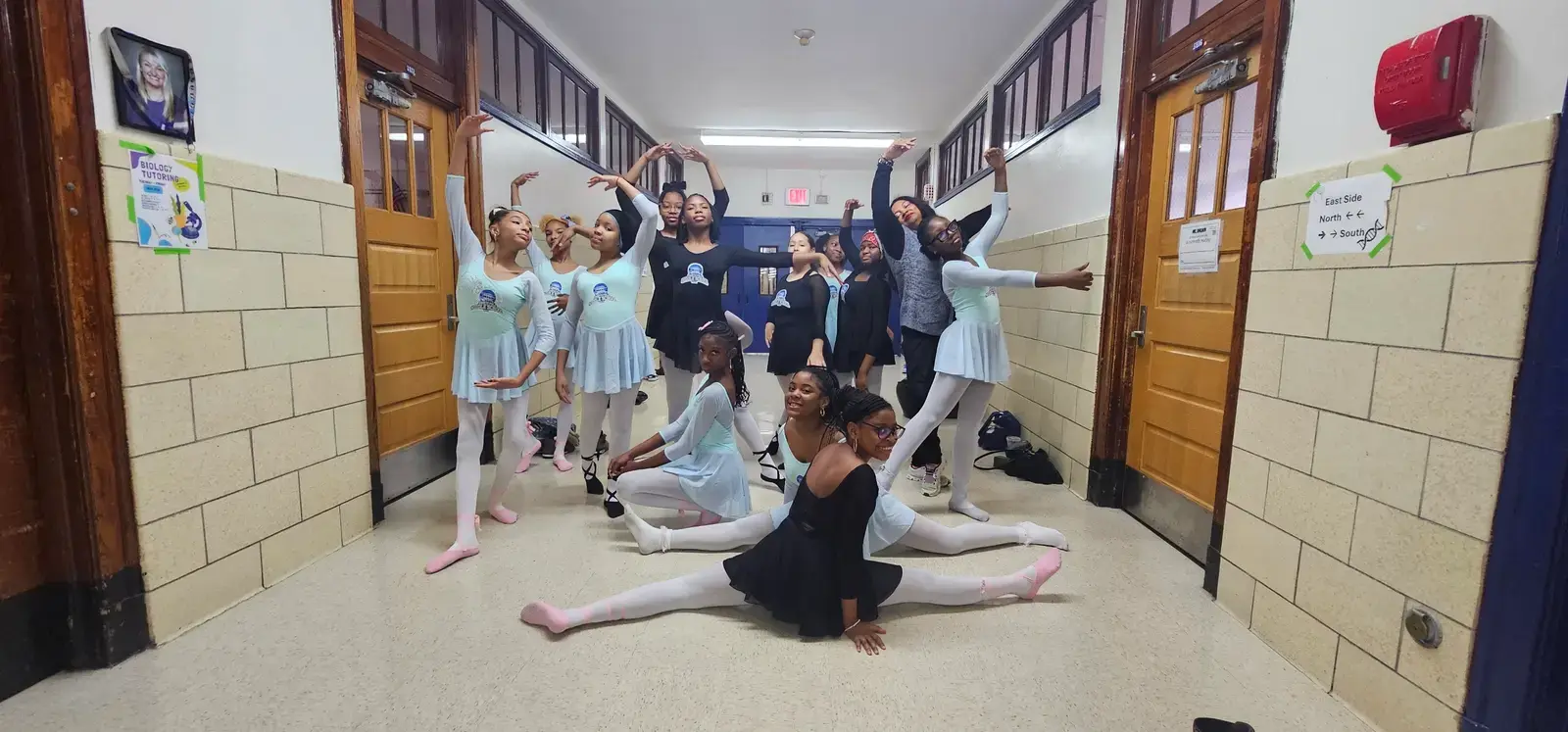 Student ballet dancers posing together in school hallway in costume