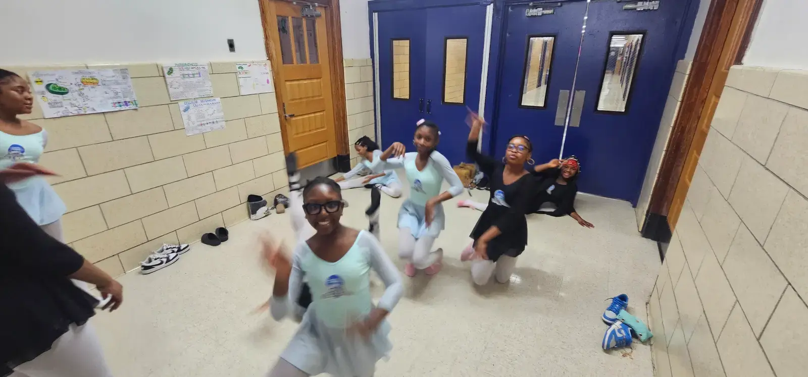 Students in ballet attire dancing together in a school hallway