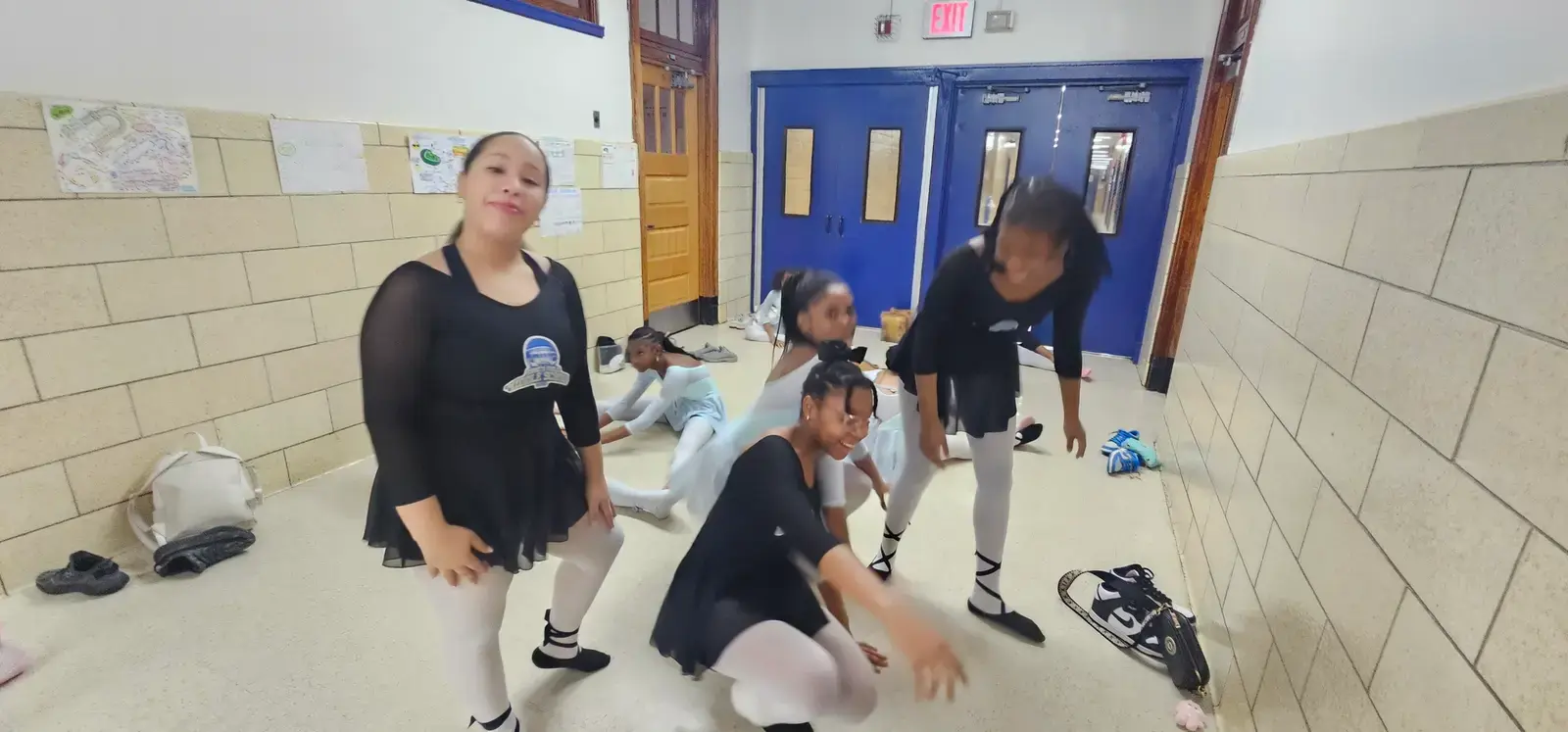 Students in ballet attire practicing dance in school hallway