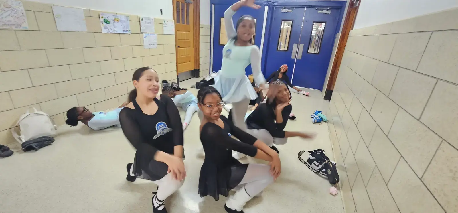 Students in dance attire practicing ballet in school hallway