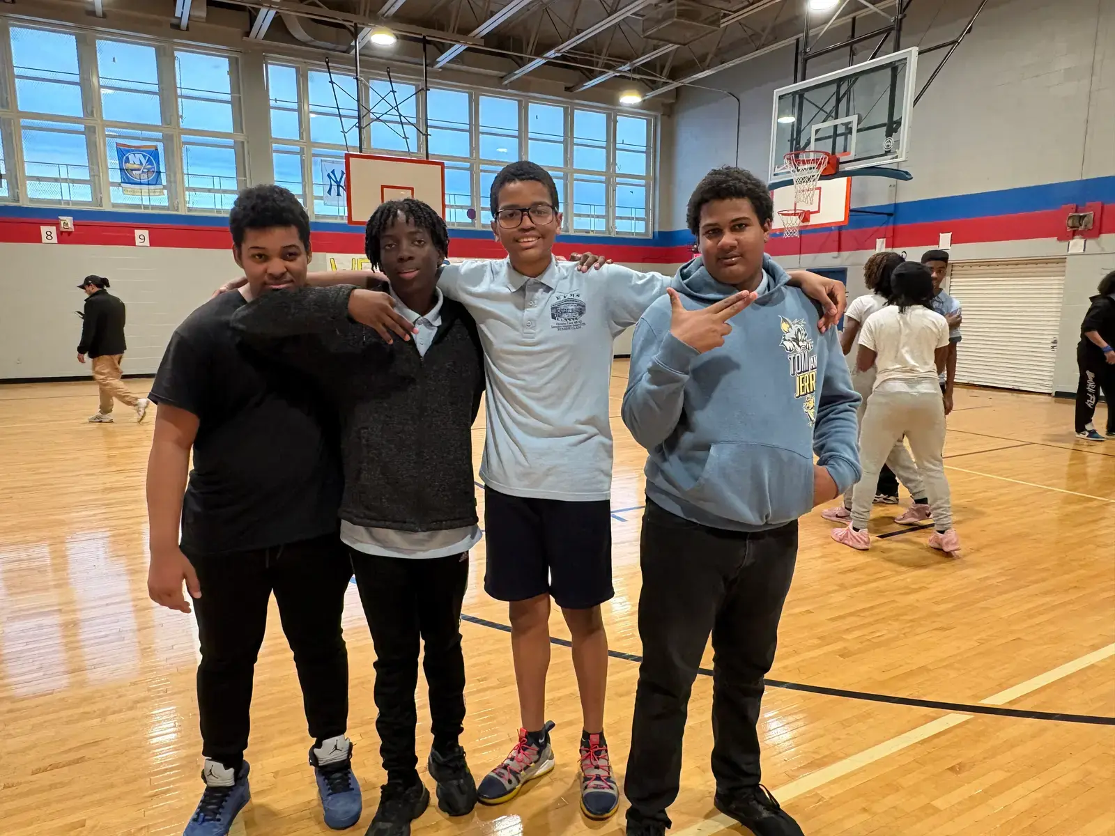 Four students smiling together in the school gymnasium