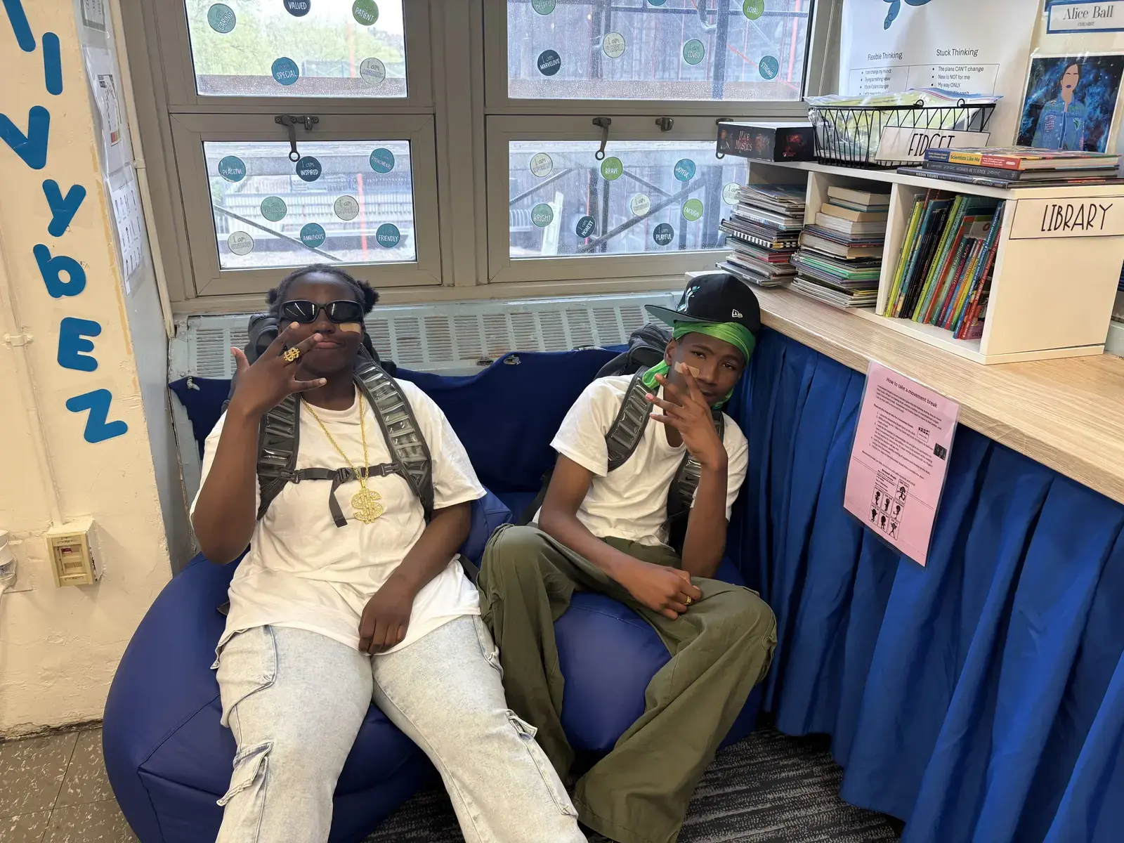 Two students posing together in a classroom reading corner