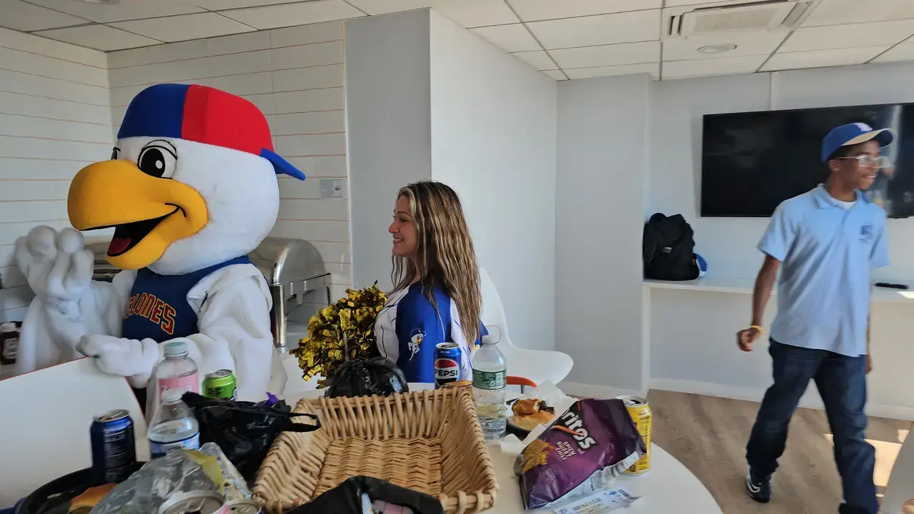 School mascot bird costume posing with cheerleader at refreshment table