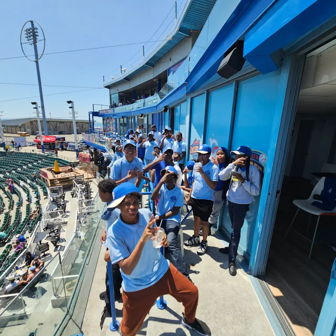 Students in blue shirts posing on stadium concourse field trip