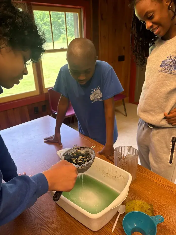 Students straining liquid during a hands-on science experiment indoors