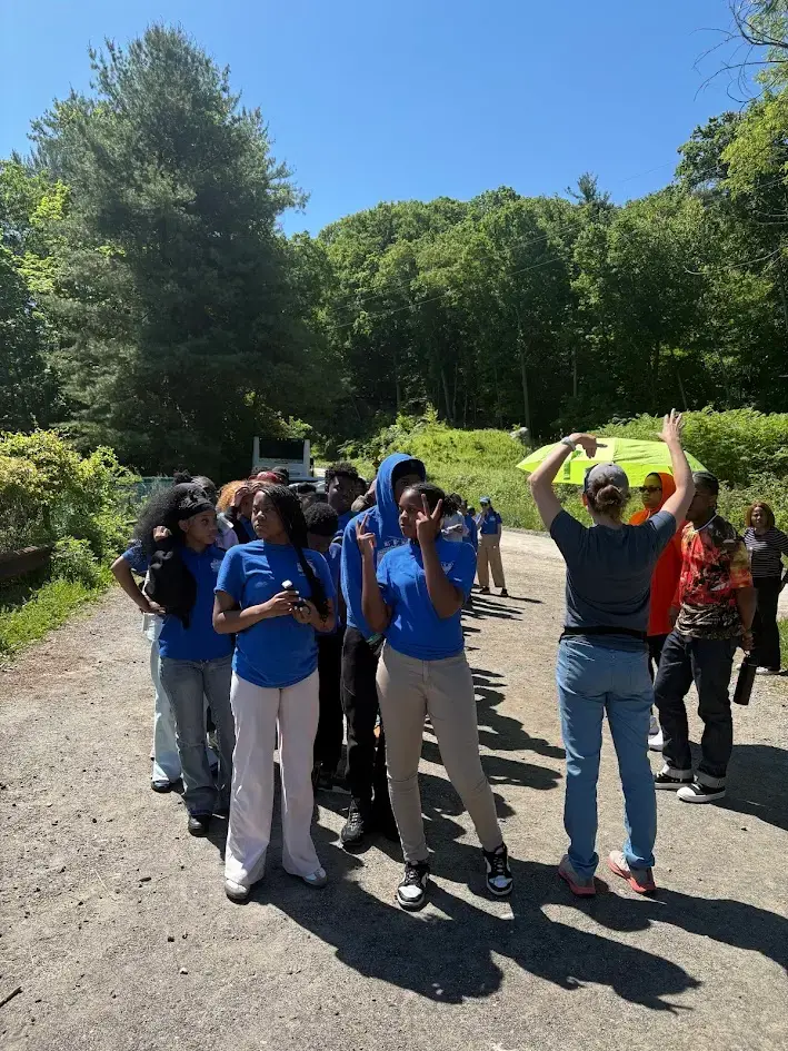 Students in blue shirts gather outdoors during a school field trip
