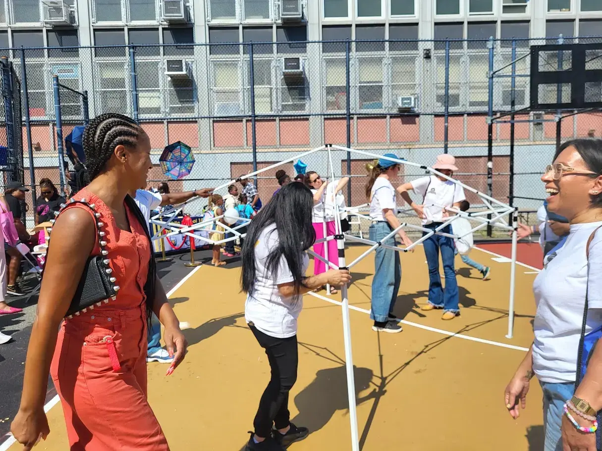 Adults setting up canopy tents on school outdoor basketball court