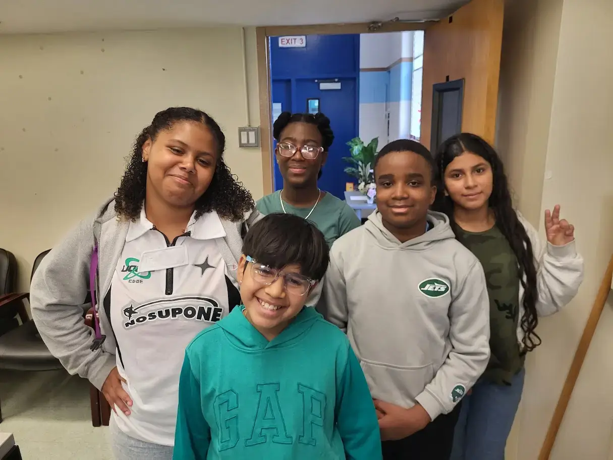 Five middle school students smiling together near school hallway exit