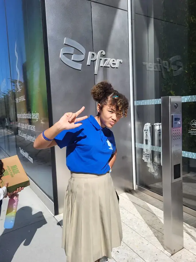 Student in school uniform posing outside Pfizer headquarters on field trip