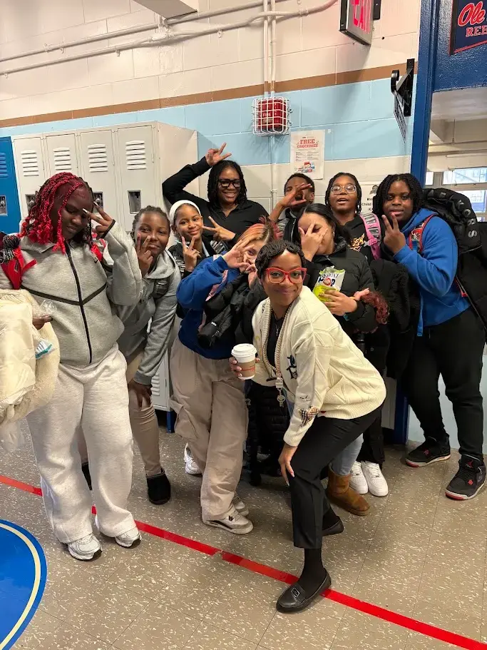 Students and a staff member pose together in school hallway