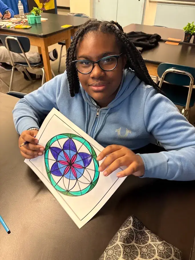 Student displaying completed colorful mandala artwork in art class