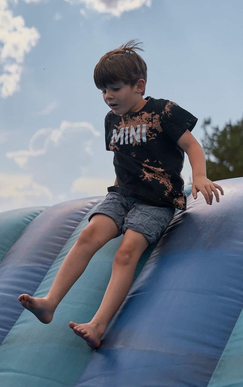 Boy happily sliding down a slide, outside.