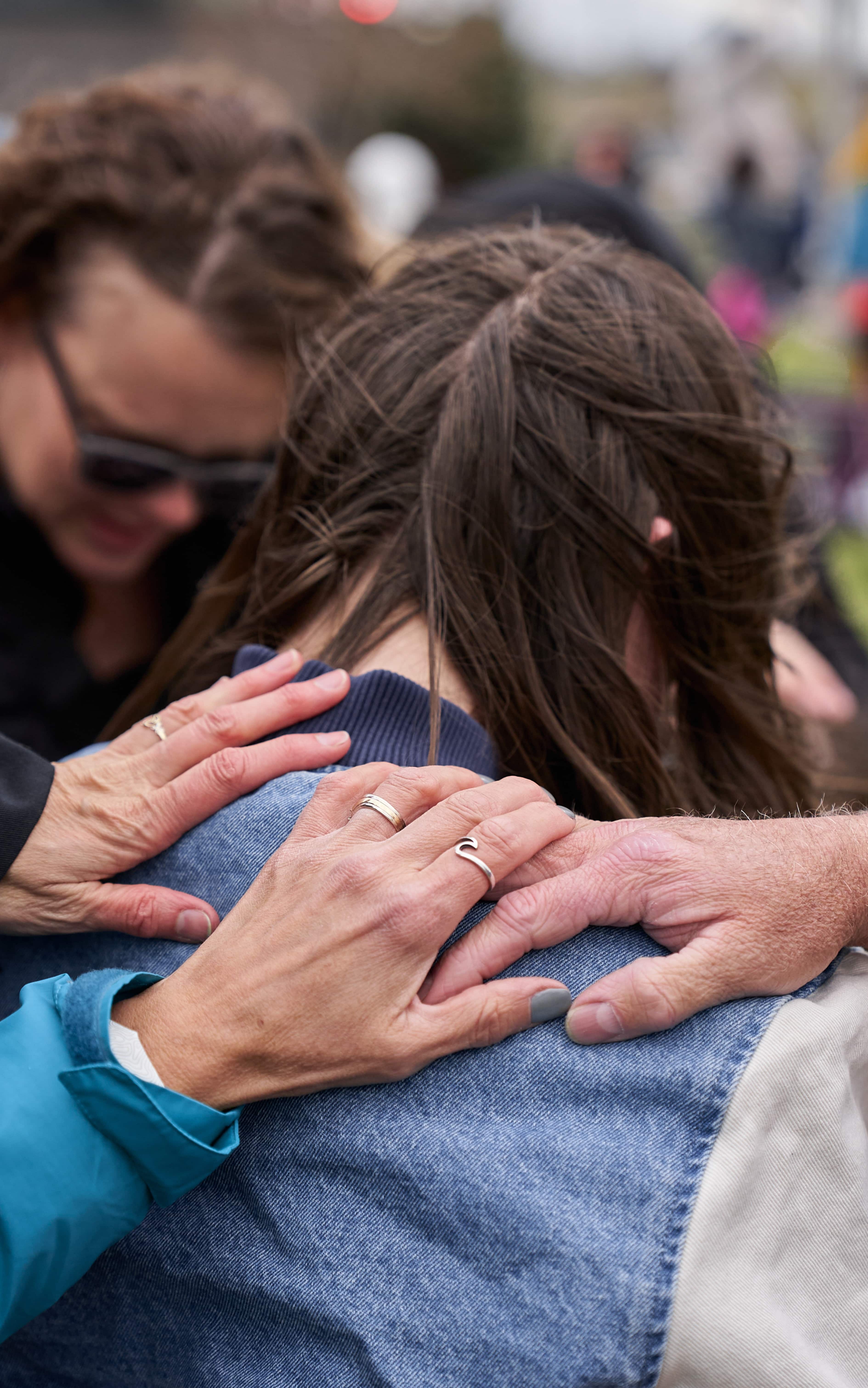 Many people laying hands over a woman, praying over her.