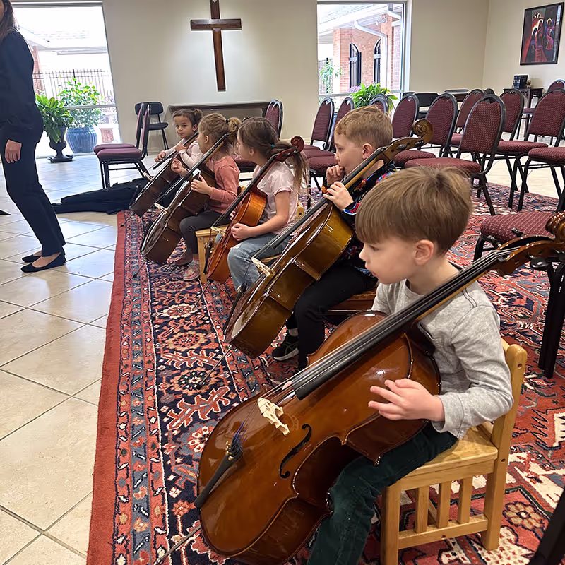 Children ages four and five playing cello and violin in preschool class music program