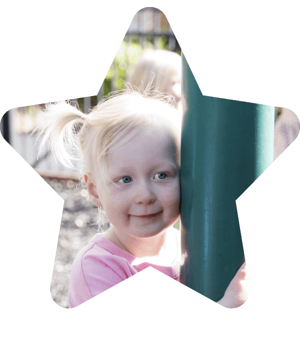 A two-year-old girl smiling while on a playground