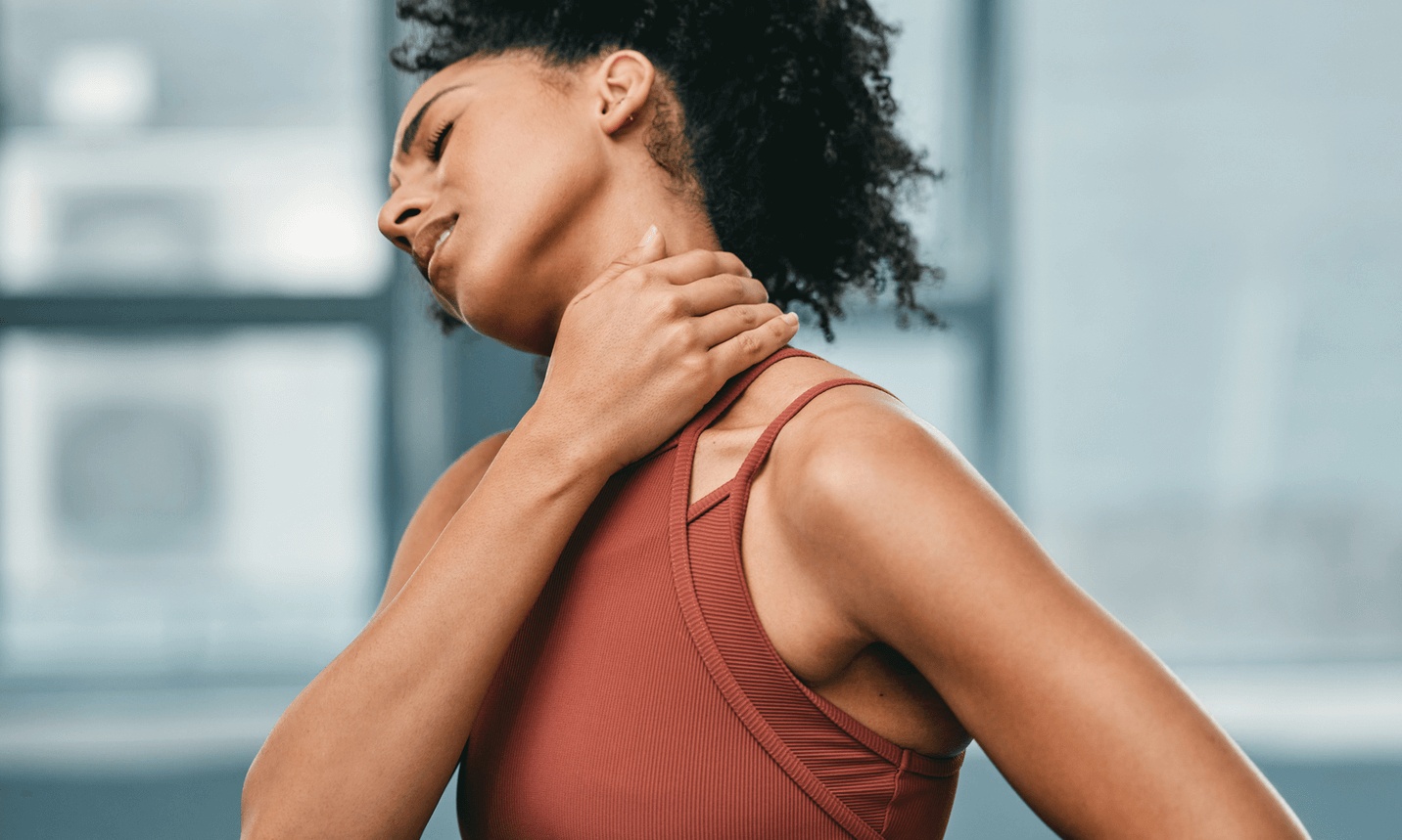 Woman holding her neck in pain after a workout, illustrating chronic neck discomfort and treatment options with the best pain management doctor in Los Angeles.