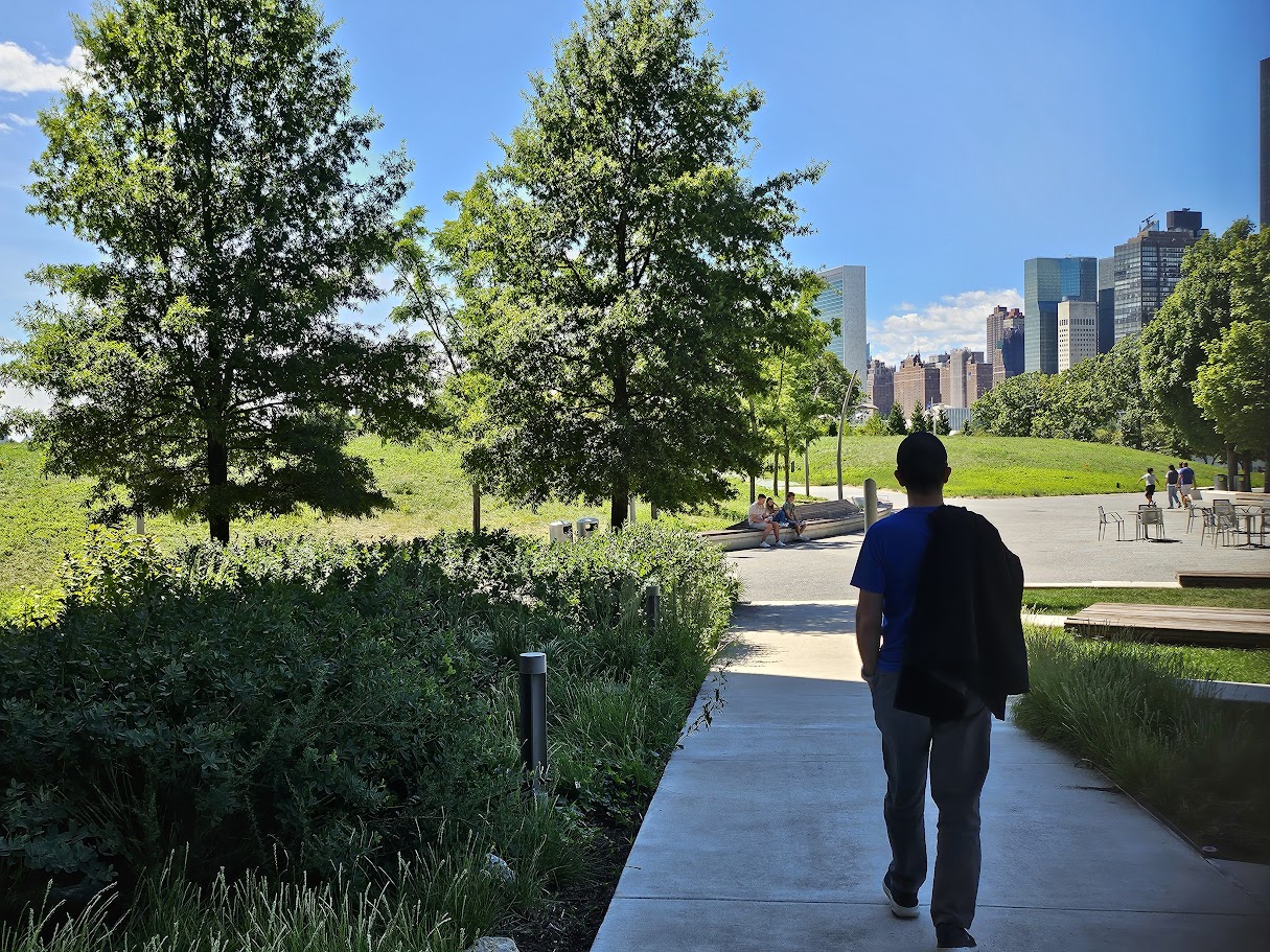 man walking in campus with cityscape and trees
