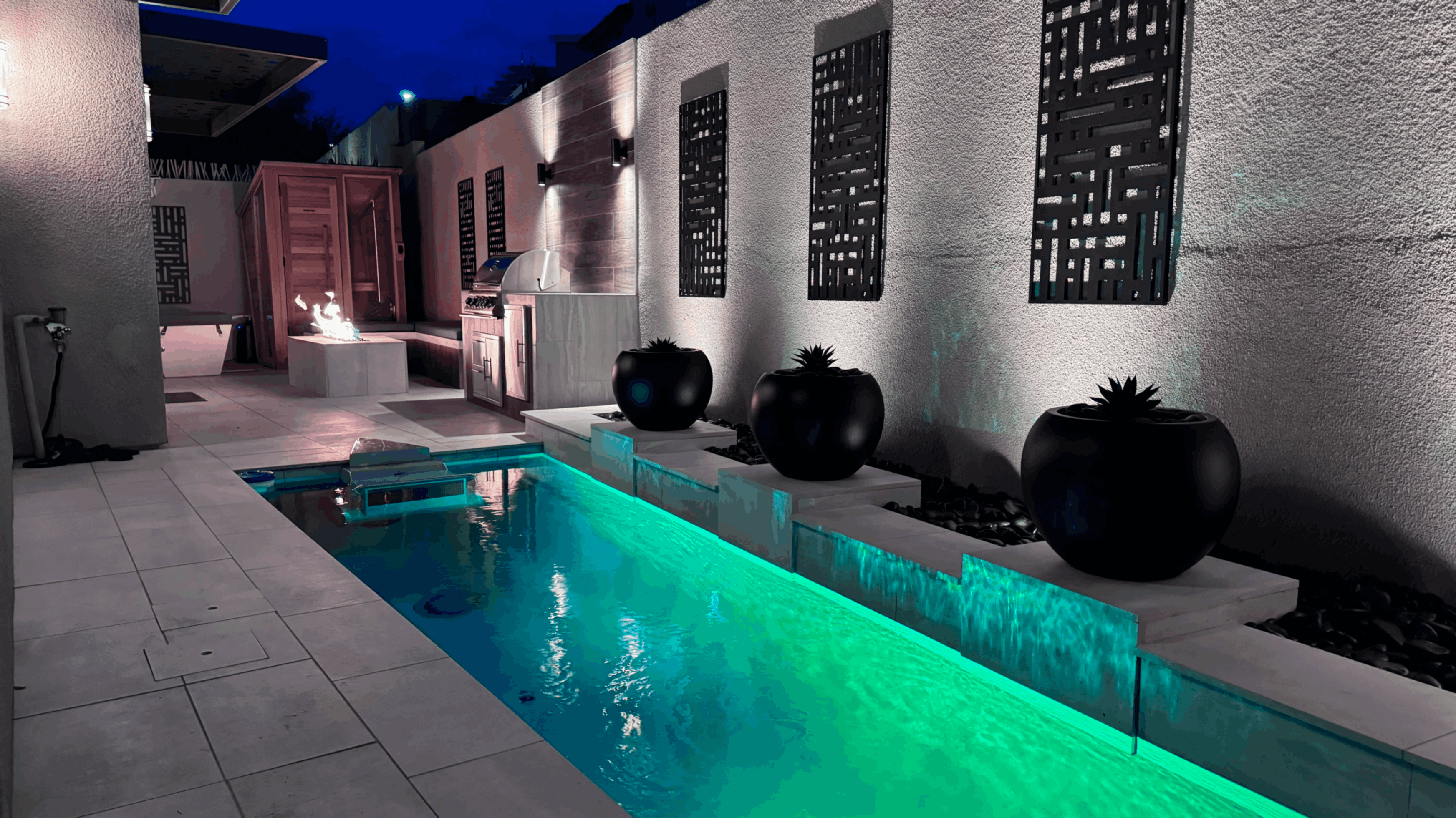 Intimate backyard spa with granite borders, nestled in a landscaped area with small plants and stone accents