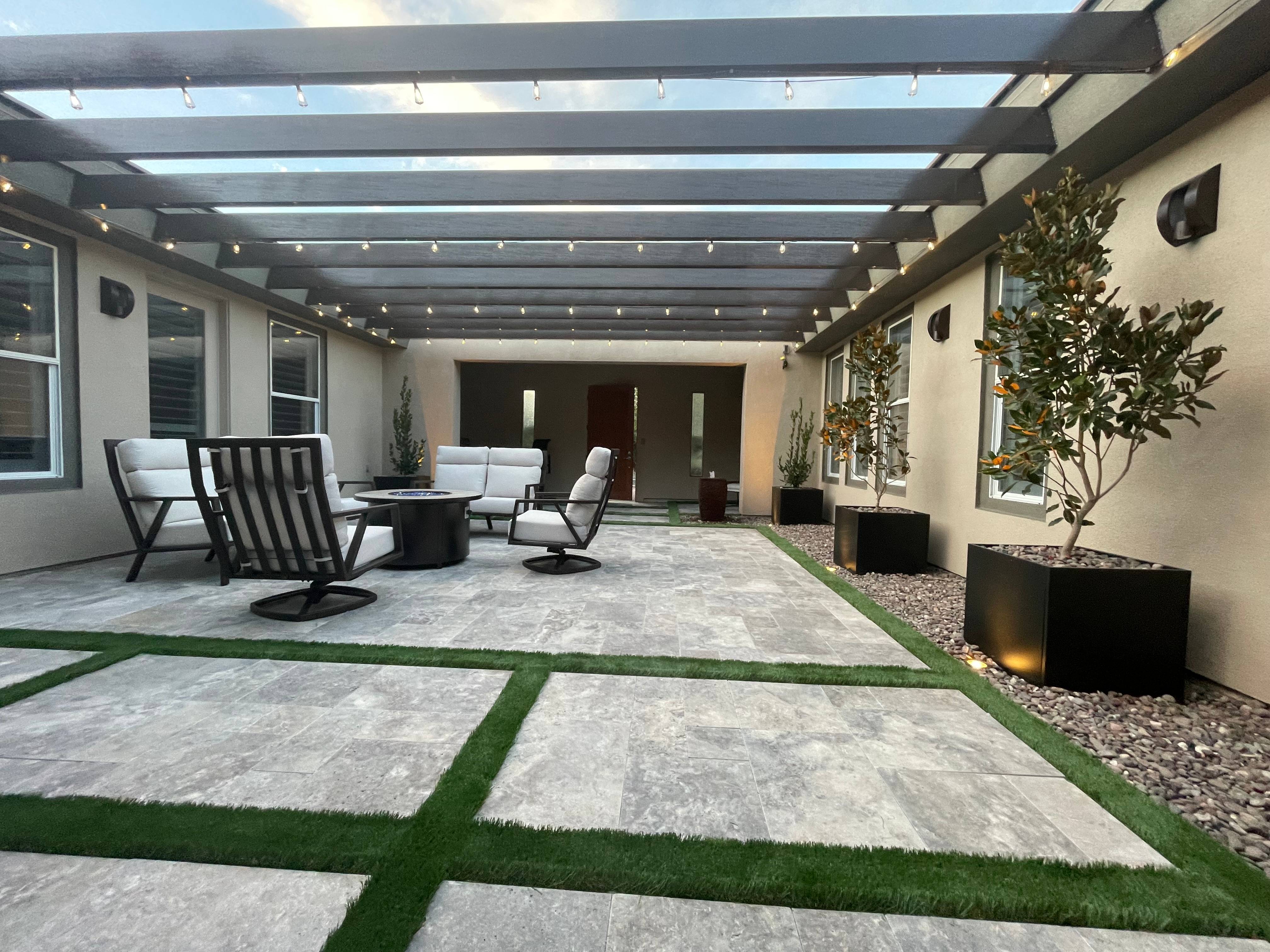 Spacious backyard patio with ambient lighting, modern fire pit, and comfortable seating