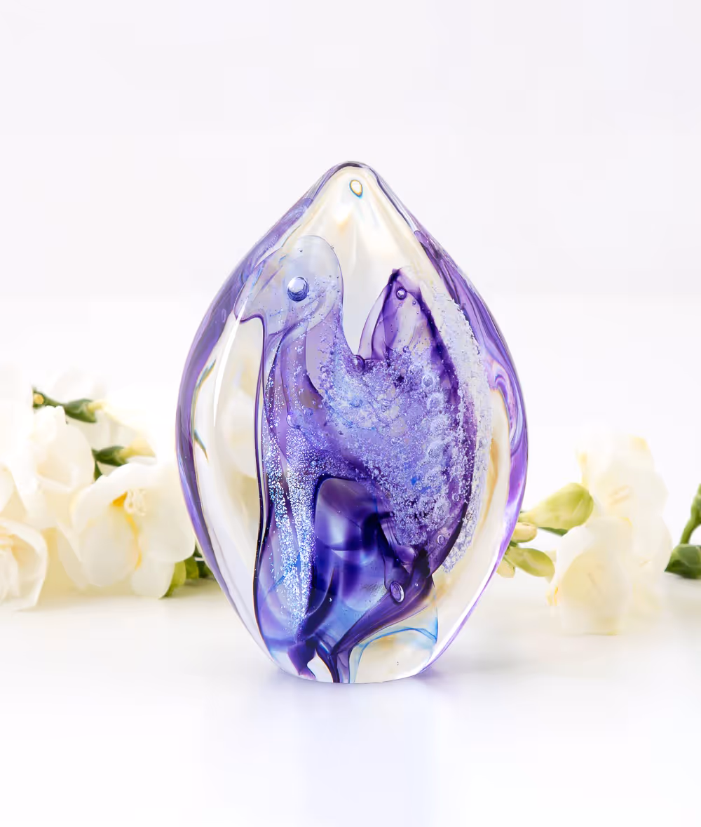 A purple glass vase sitting next to white flowers.