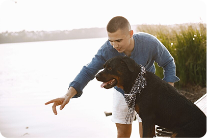 Trainer giving hand signal to dog during outdoor session near lake