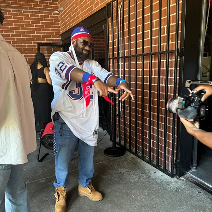 Man dressed in throwback sportswear posing for a photographer.