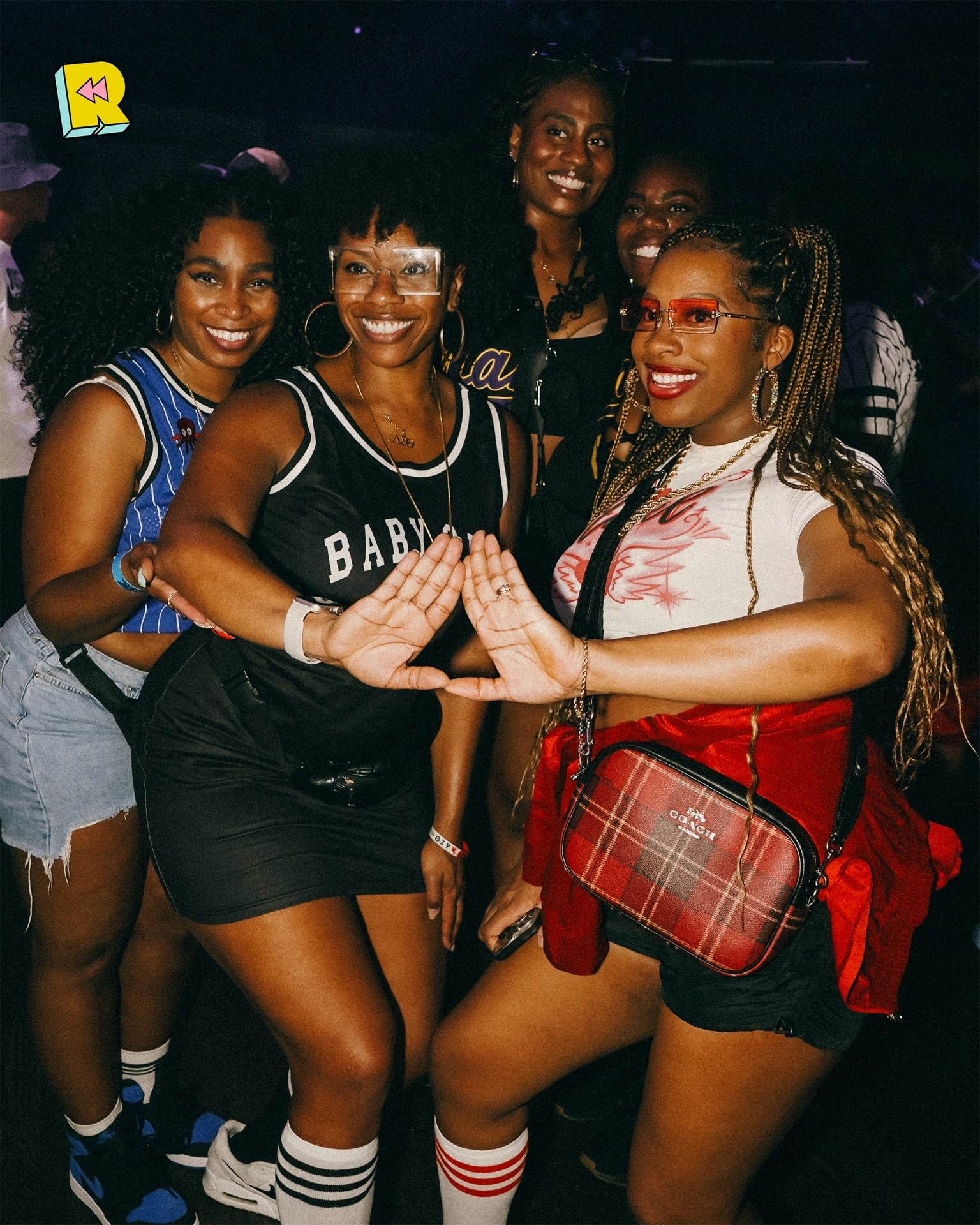 Group of women smiling and posing at Rewind in throwback outfits, radiating joy and nostalgic energy on the dance floor.